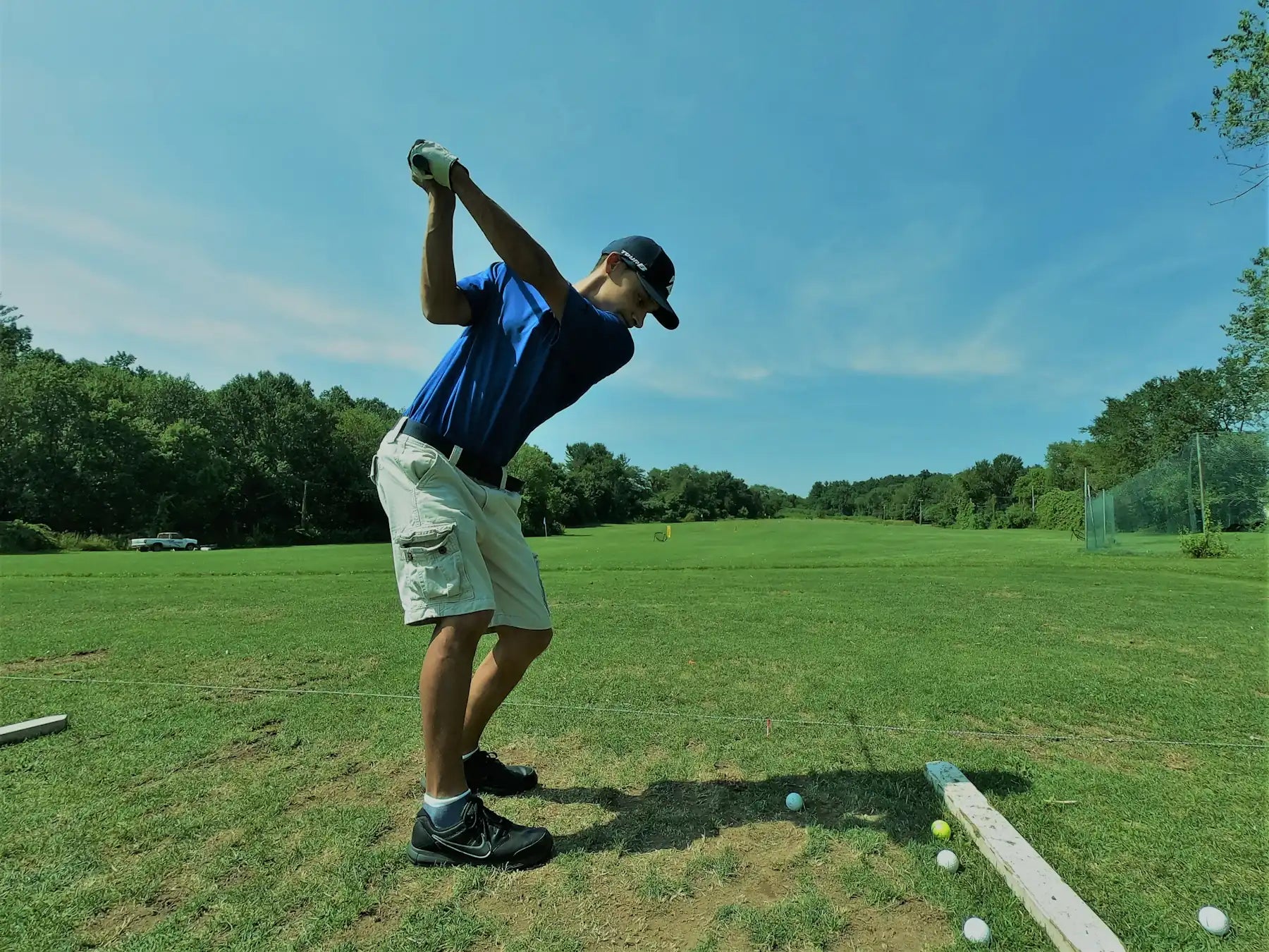 Golfer in a blue polo teeing off on a sunlit course